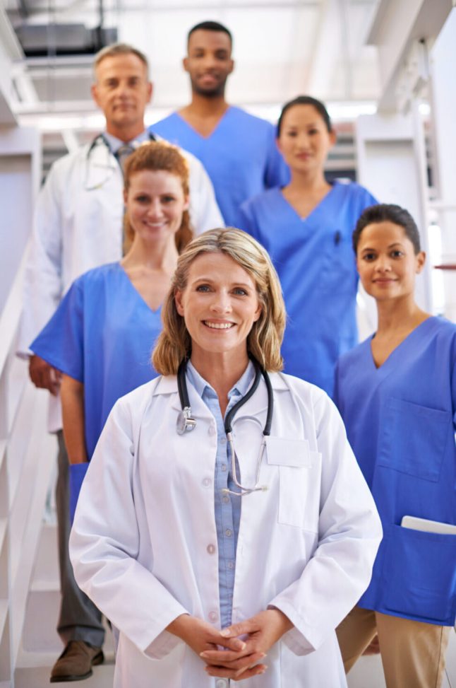 Portrait of a diverse team of medical professionals standing on a staircase in a hospital.